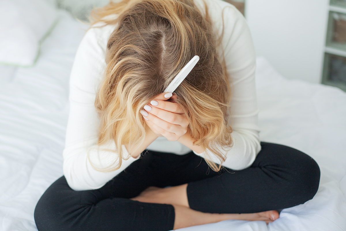 A disappointed woman holds a pregnancy test, introducing the topic for the fertility blog: IVF Didn't Work, Now What?