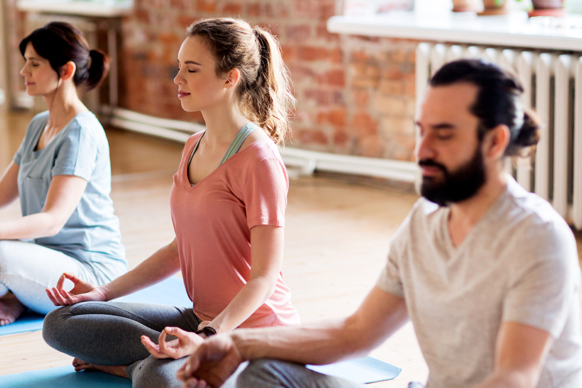 A group of adults practices yoga to reduce stress and improve fertility.