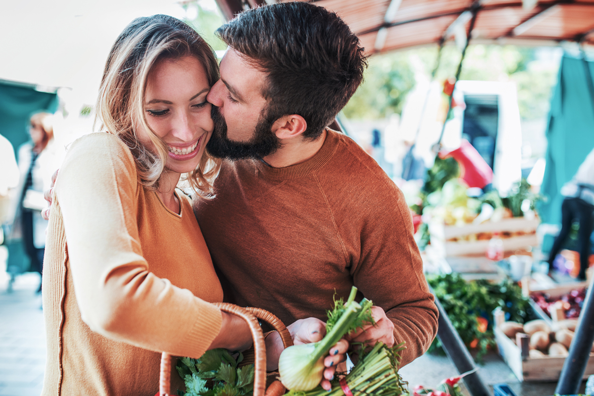 A happy couple shops for healthy food together to improve fertility naturally.