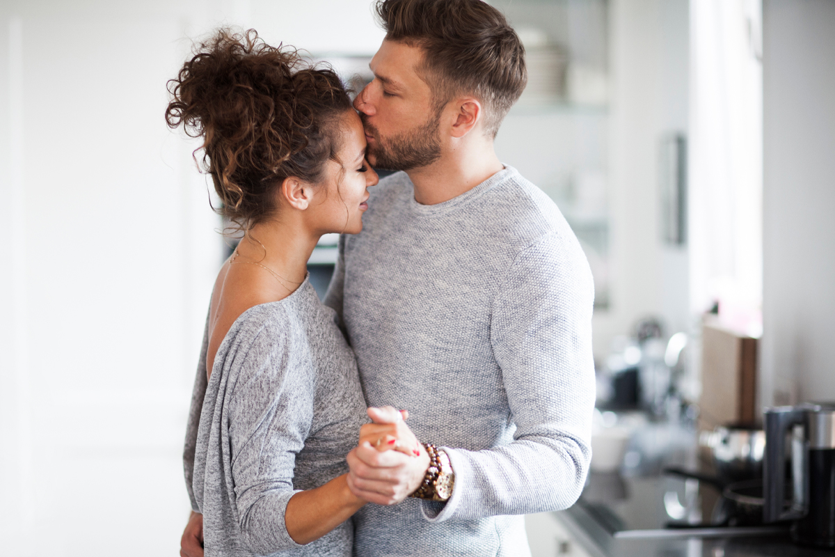 A loving couple dances together in a living room.