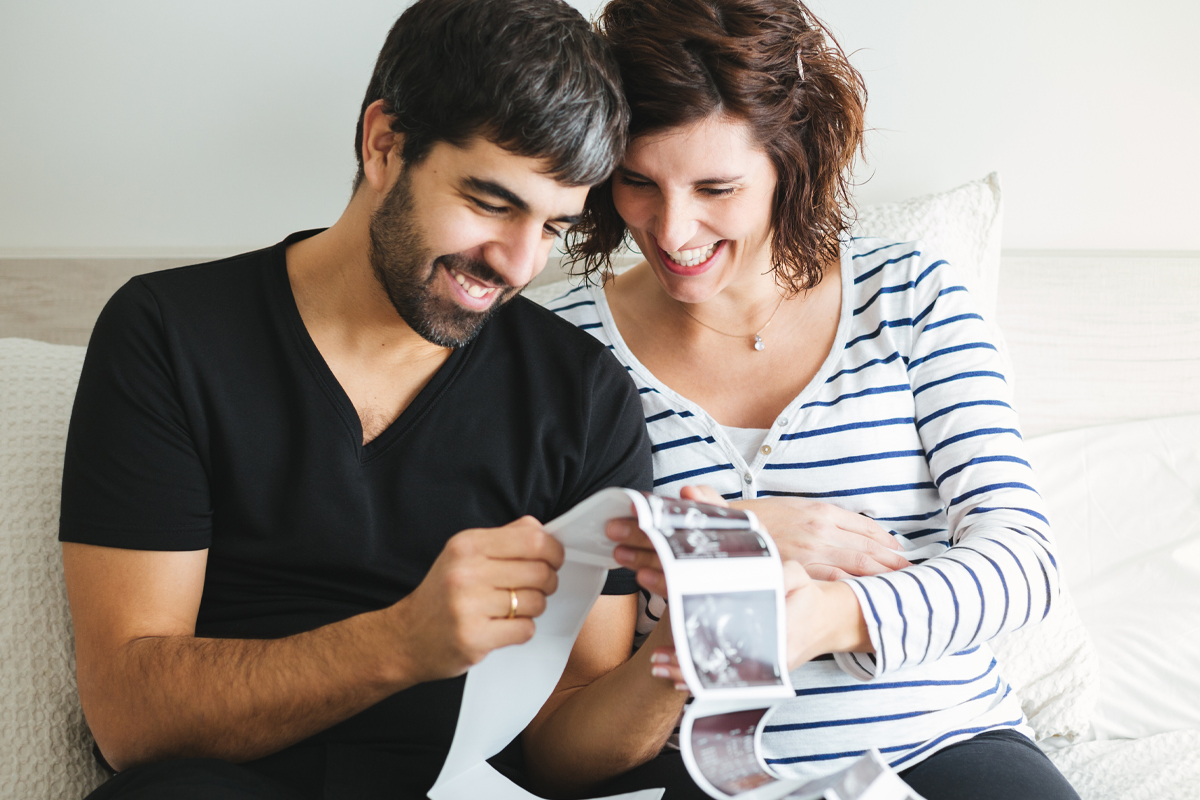 A happy couple reviews sonogram photos after getting pregnant with the help of online fertility coaching. 